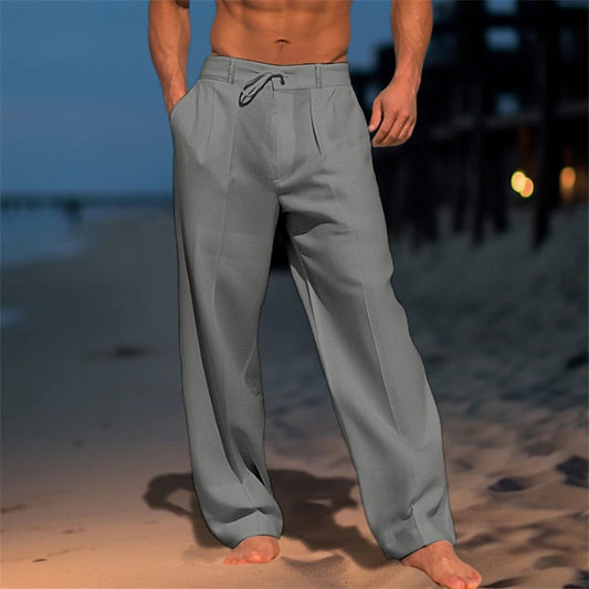 Pantalon Large Nairo gris, porté pieds nus sur la plage au crépuscule